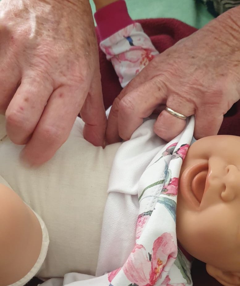 Hände halten ein Baby sanft in einem Tuch