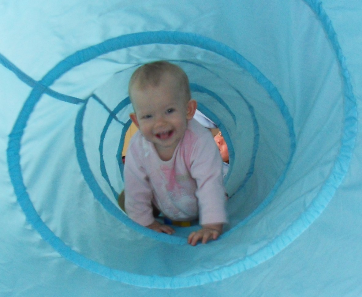 Baby krabbelt durch einen blauen Stofftunnel