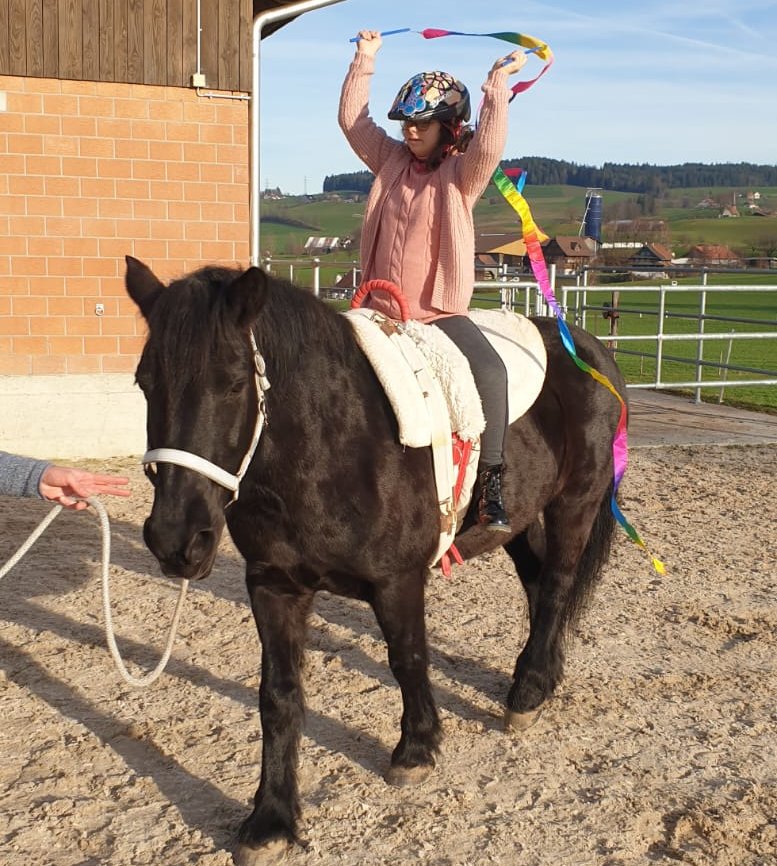 Kind mit Helm reitet auf einem Pony